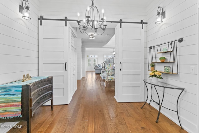 entrance foyer with ceiling fan, wood-type flooring, a barn door, and wood walls