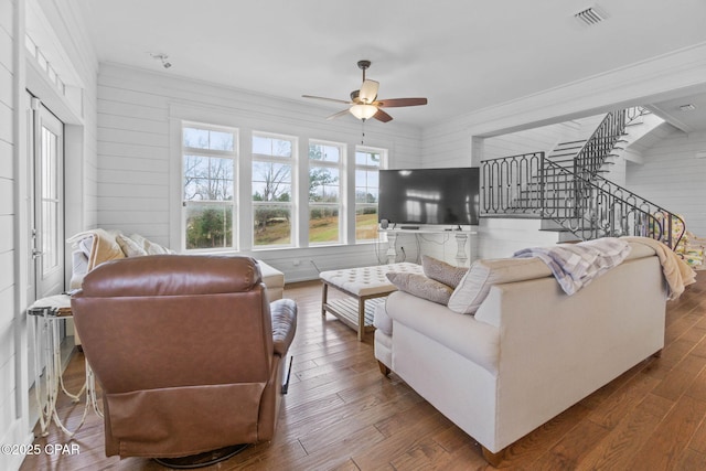 living room with wood-type flooring, ornamental molding, and ceiling fan