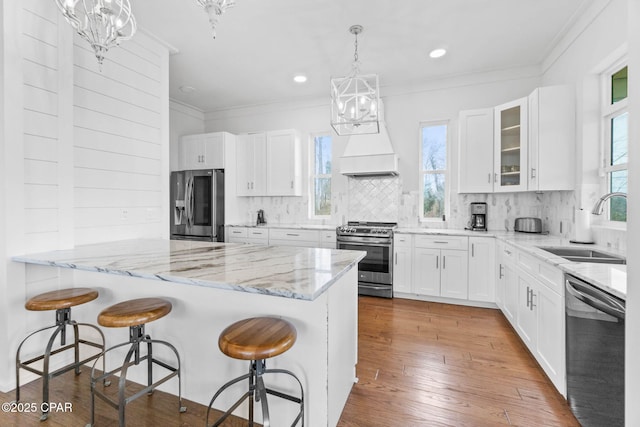 kitchen with an inviting chandelier, appliances with stainless steel finishes, sink, and white cabinets