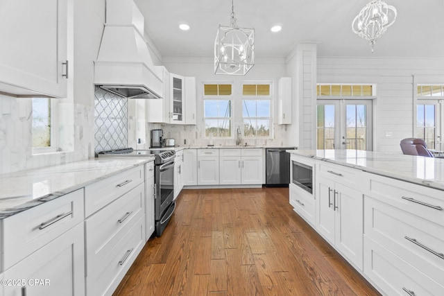 kitchen featuring premium range hood, white cabinets, appliances with stainless steel finishes, and a notable chandelier