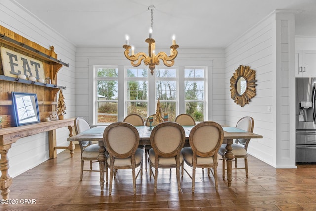 dining room featuring dark hardwood / wood-style flooring, crown molding, wooden walls, and a chandelier