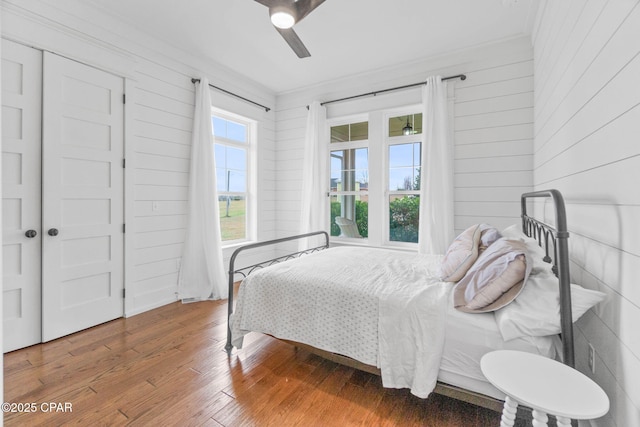 bedroom with multiple windows, hardwood / wood-style floors, ceiling fan, and a closet