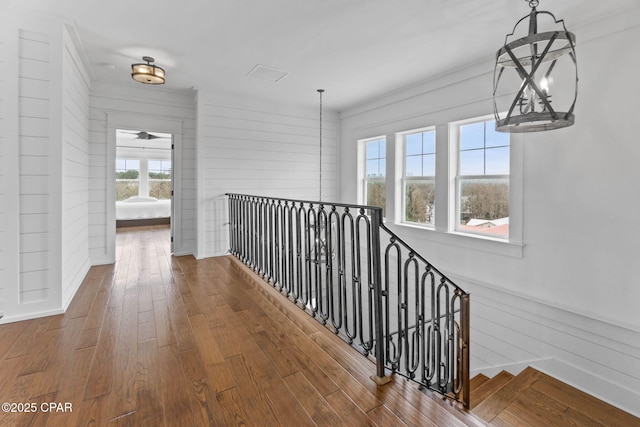 hall with hardwood / wood-style flooring, ornamental molding, and wood walls