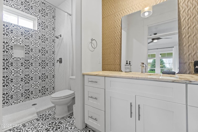 bathroom featuring vanity, a tile shower, a wealth of natural light, and toilet