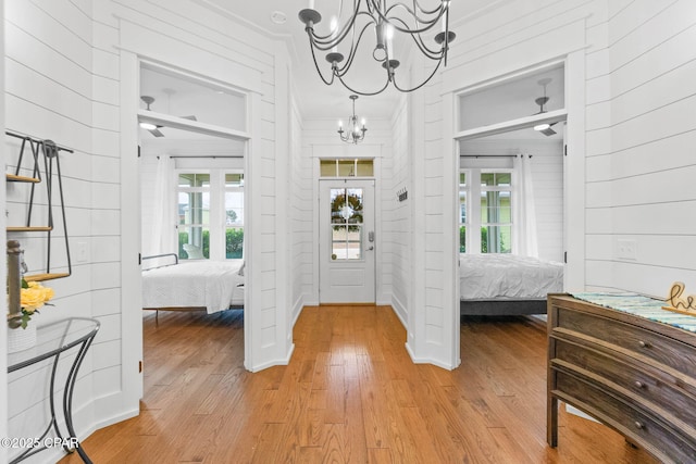 foyer featuring plenty of natural light, light hardwood / wood-style flooring, a chandelier, and wood walls