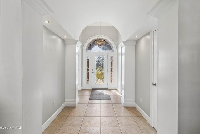 tiled foyer with ornate columns, vaulted ceiling, and a chandelier