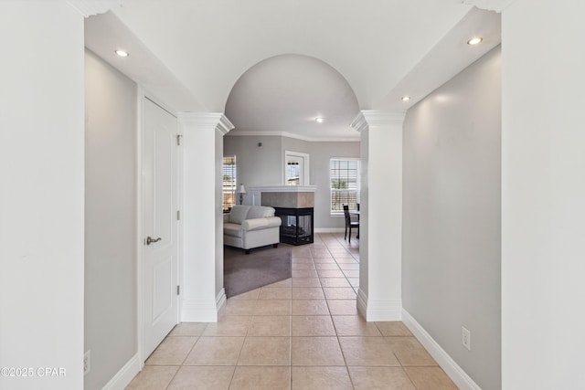 hall featuring light tile patterned floors, crown molding, and decorative columns