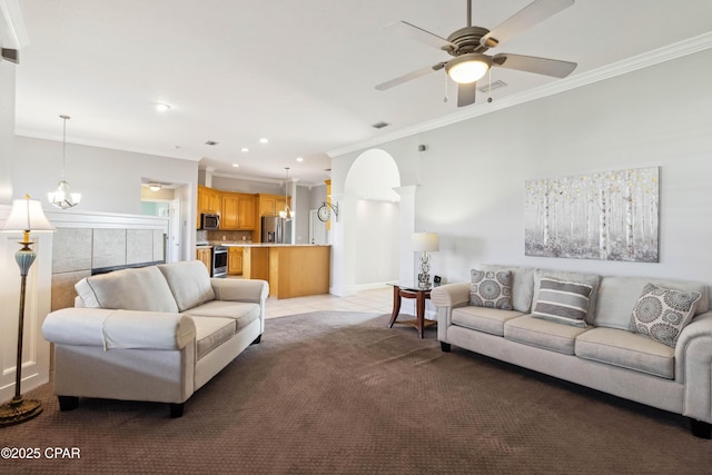 carpeted living room with ceiling fan with notable chandelier, ornamental molding, and decorative columns