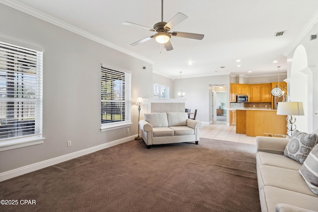 carpeted living room with ceiling fan with notable chandelier and ornamental molding