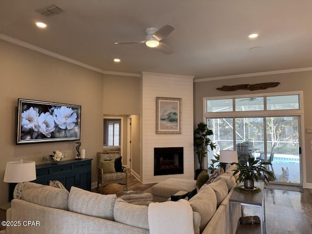 living room with hardwood / wood-style floors, a fireplace, ornamental molding, and ceiling fan