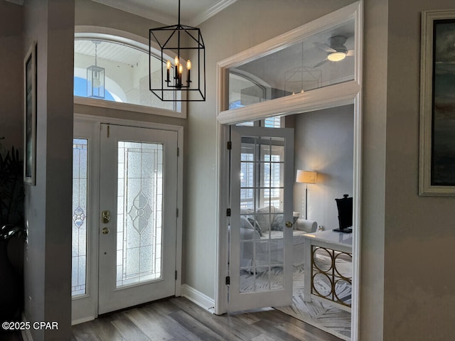 foyer featuring wood-type flooring, a notable chandelier, and crown molding