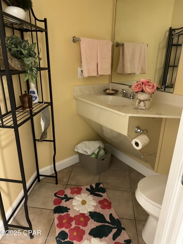 bathroom with tile patterned floors, toilet, baseboards, and a sink