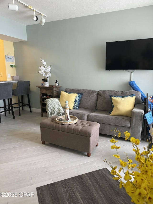 living room with track lighting, a textured ceiling, baseboards, and wood tiled floor