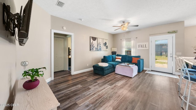 living room featuring ceiling fan, dark wood-type flooring, and a textured ceiling