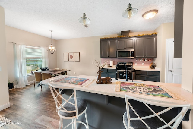 kitchen with hanging light fixtures, stainless steel appliances, a kitchen breakfast bar, and kitchen peninsula