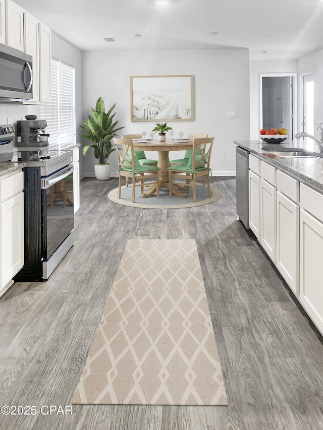 kitchen with appliances with stainless steel finishes, light stone countertops, sink, and white cabinets