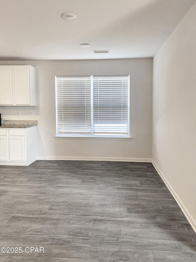 unfurnished dining area with dark wood-type flooring