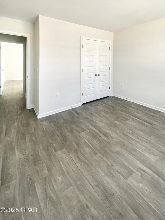 unfurnished bedroom with dark hardwood / wood-style flooring and a closet