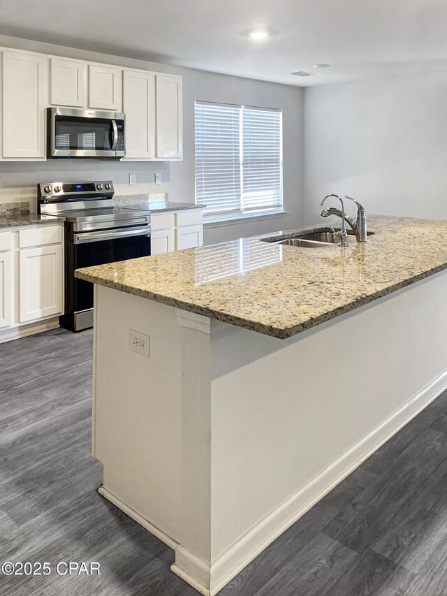 kitchen with light stone counters, appliances with stainless steel finishes, sink, and white cabinets