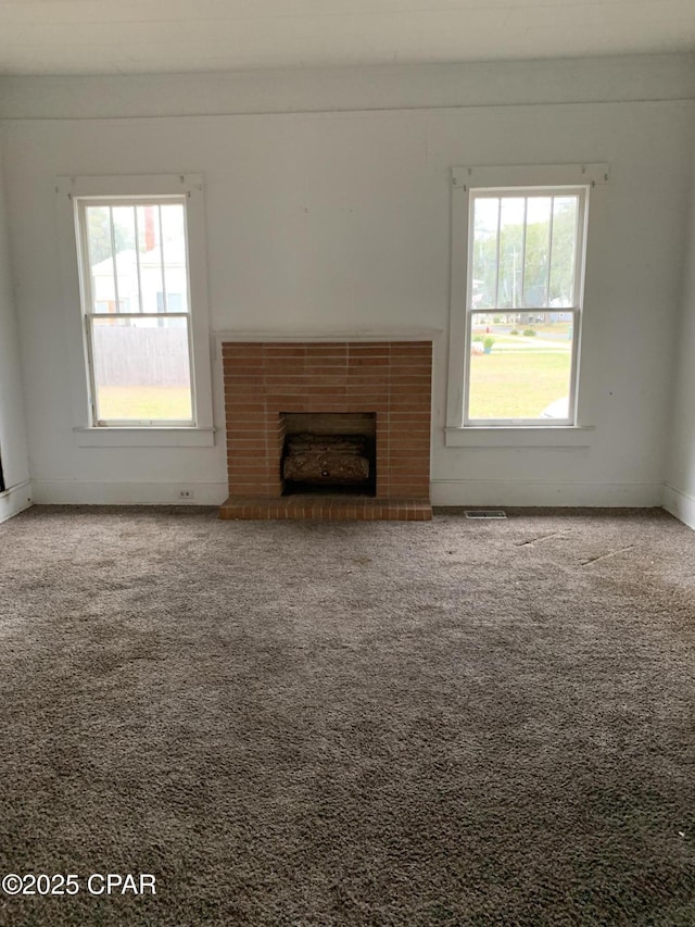 unfurnished living room featuring baseboards, a brick fireplace, and carpet