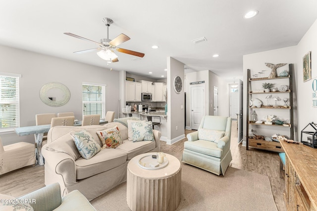 living room with ceiling fan, plenty of natural light, and light wood-type flooring