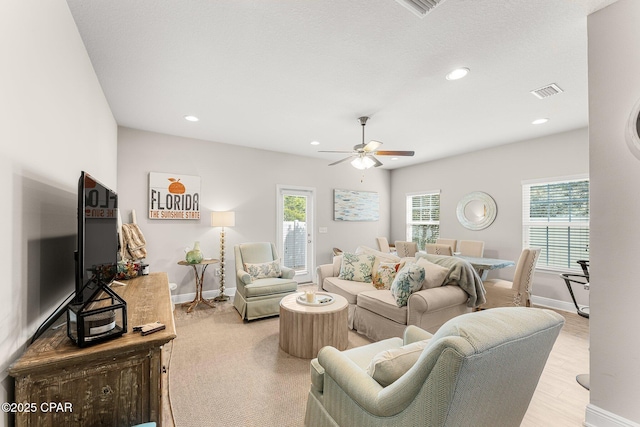 living room with light hardwood / wood-style flooring, plenty of natural light, and ceiling fan