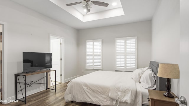 bedroom with dark wood-type flooring and a tray ceiling