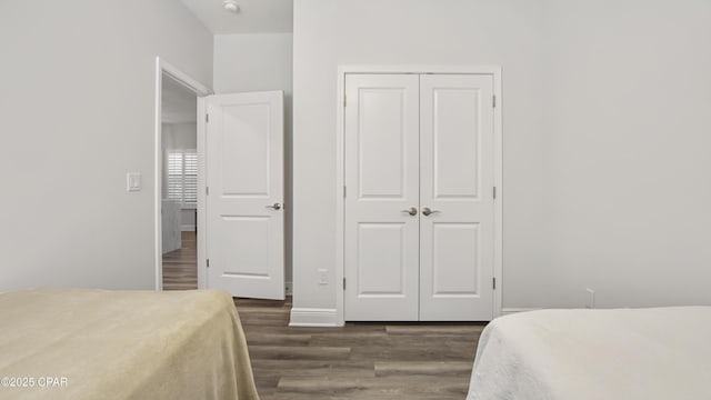 bedroom with dark hardwood / wood-style flooring and a closet