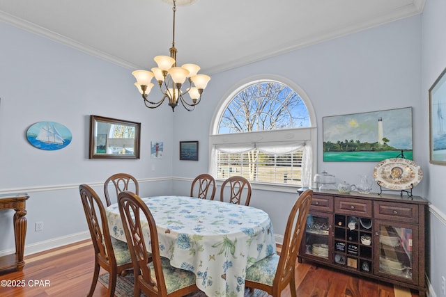 dining space with baseboards, ornamental molding, a chandelier, and wood finished floors