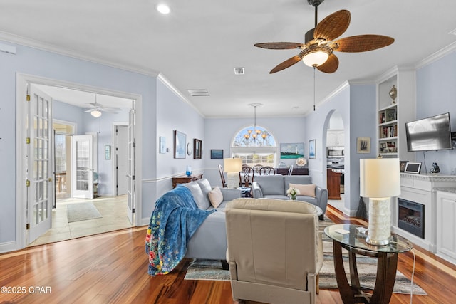 living room with light wood-style floors, visible vents, a fireplace, and ornamental molding