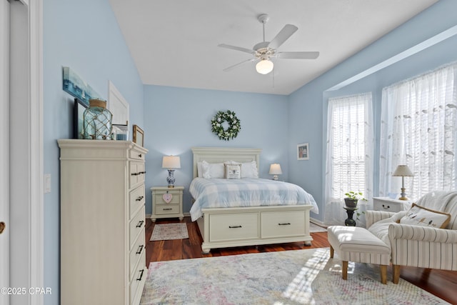 bedroom with dark wood finished floors, a ceiling fan, and baseboards