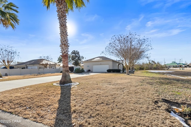 view of front facade featuring driveway, a garage, fence, and a front lawn