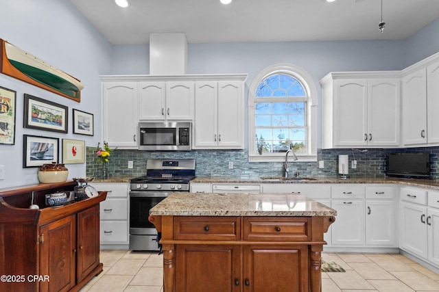 kitchen featuring appliances with stainless steel finishes, a center island, white cabinets, and a sink