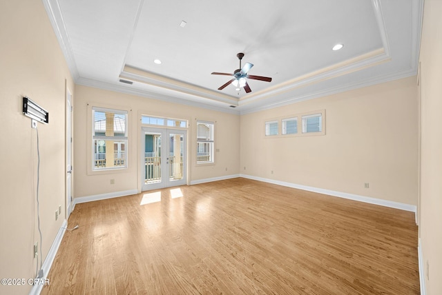 spare room with ceiling fan, ornamental molding, light hardwood / wood-style floors, french doors, and a raised ceiling