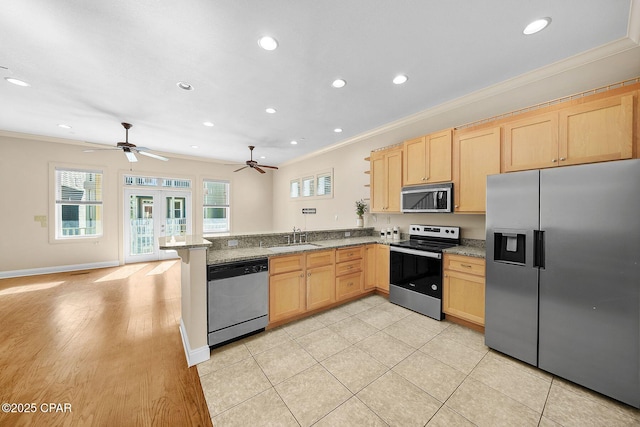 kitchen with stainless steel appliances, sink, light stone counters, and kitchen peninsula