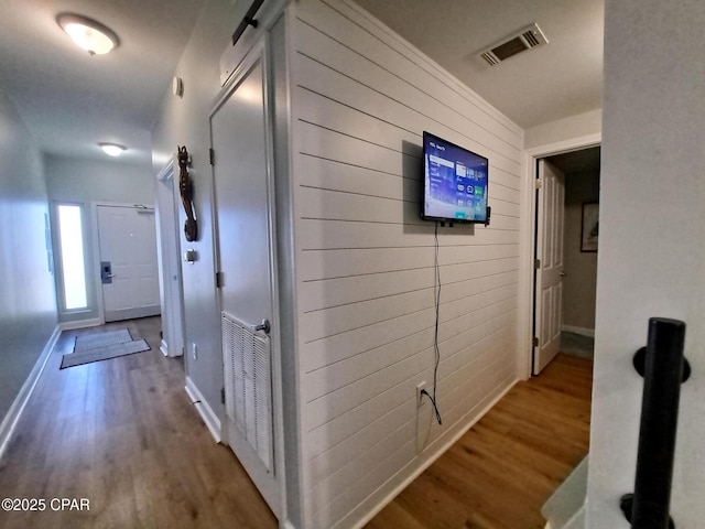 hall with hardwood / wood-style flooring, a barn door, and wooden walls