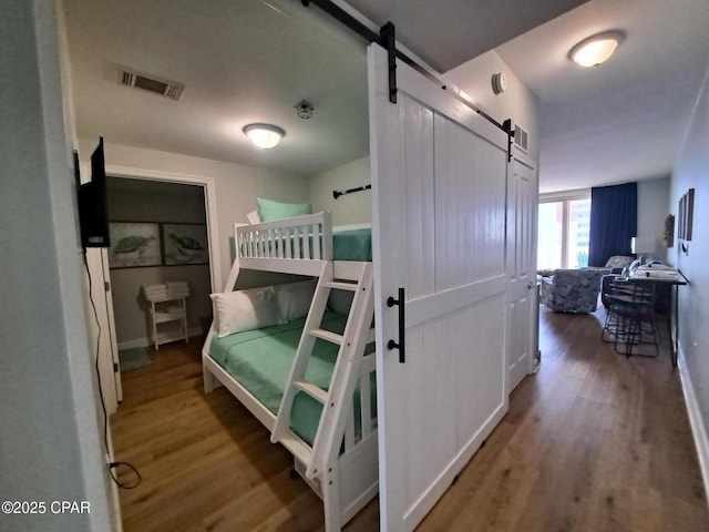 bedroom with hardwood / wood-style flooring and a barn door