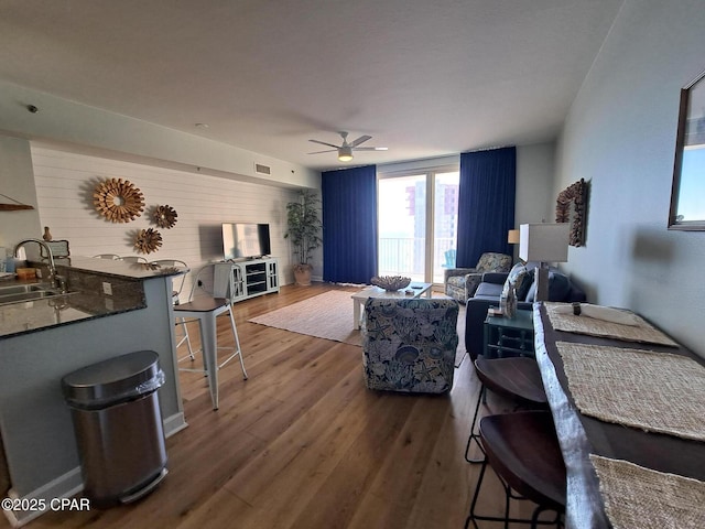 living room featuring ceiling fan, wood-type flooring, and sink