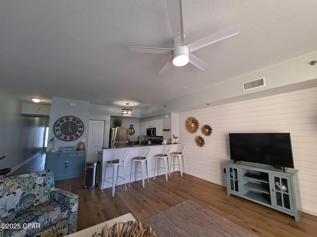 living room featuring a textured ceiling, dark hardwood / wood-style floors, and ceiling fan