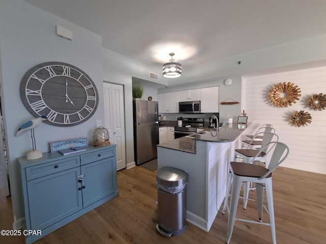 kitchen featuring appliances with stainless steel finishes, a breakfast bar, white cabinets, kitchen peninsula, and blue cabinetry