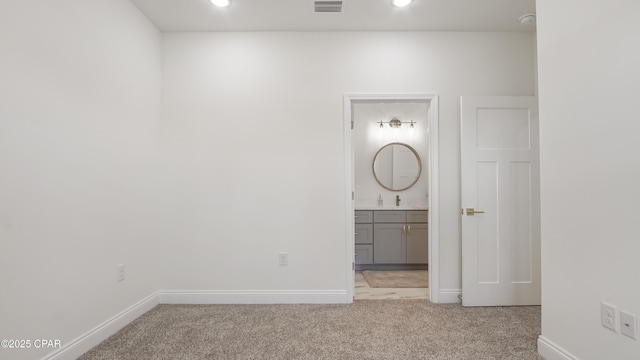 unfurnished bedroom featuring light carpet, sink, and connected bathroom