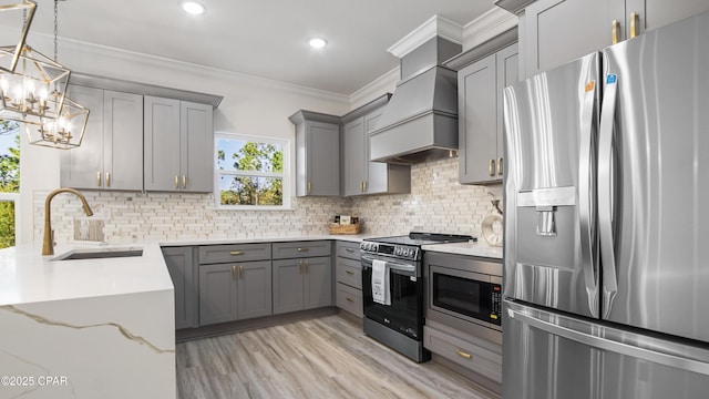 kitchen with appliances with stainless steel finishes, decorative light fixtures, sink, gray cabinetry, and custom range hood