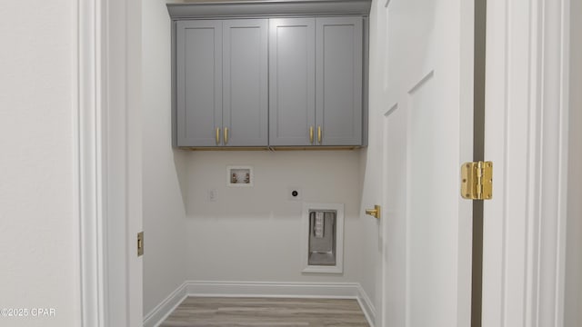 clothes washing area featuring electric dryer hookup, hookup for a washing machine, light hardwood / wood-style flooring, and cabinets