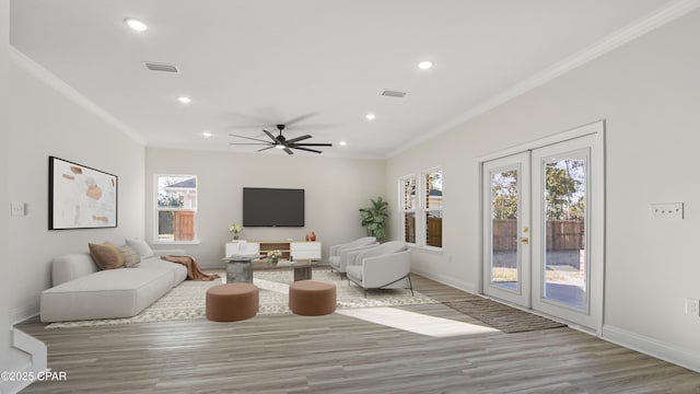 living room with french doors, ornamental molding, and light hardwood / wood-style flooring