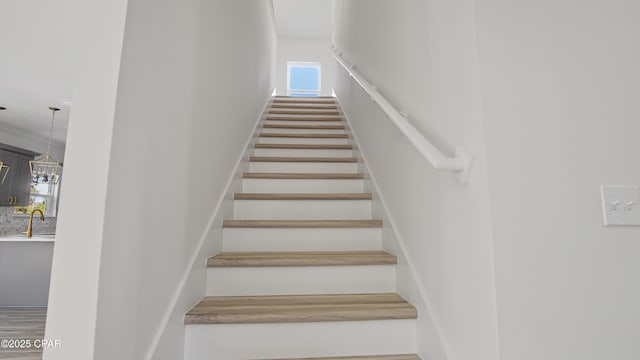 staircase with sink, crown molding, and a wealth of natural light