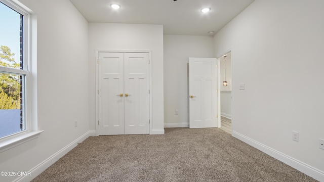 unfurnished bedroom featuring multiple windows, carpet, and a closet