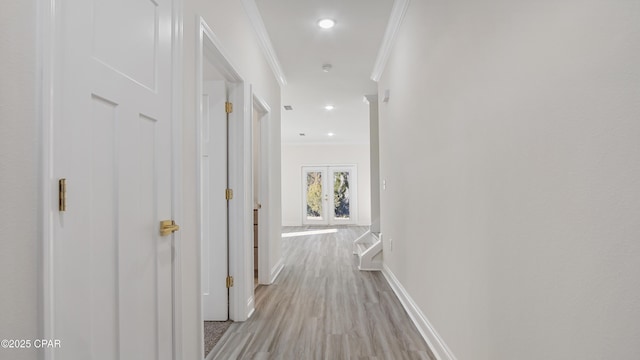 corridor with ornamental molding, french doors, and light wood-type flooring