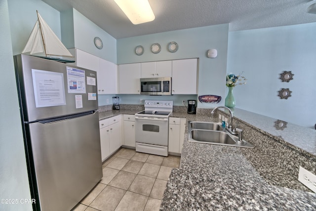 kitchen featuring sink, white cabinetry, a textured ceiling, light tile patterned floors, and stainless steel appliances