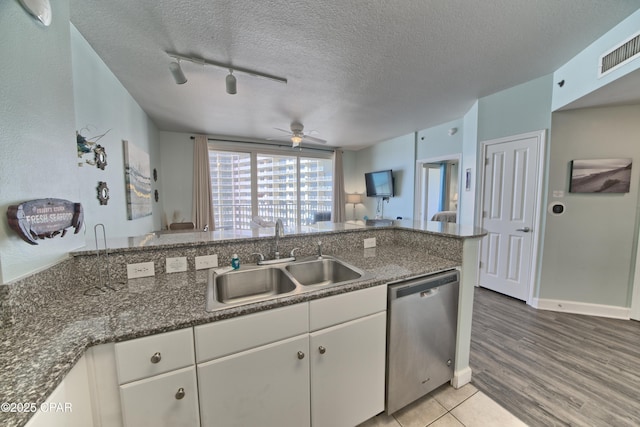 kitchen with white cabinetry, rail lighting, sink, stainless steel dishwasher, and a textured ceiling