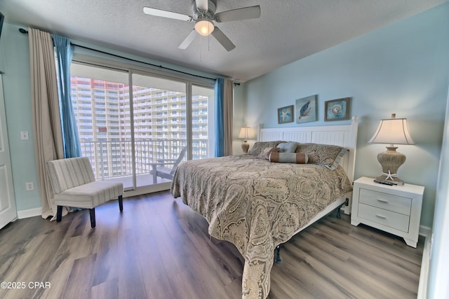 bedroom featuring dark wood-type flooring, ceiling fan, access to exterior, and a textured ceiling